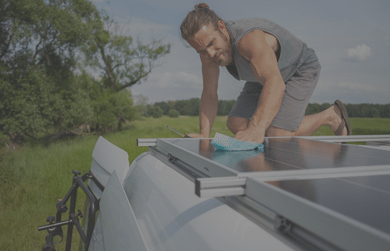 Young man polishing solar panel on top of a van